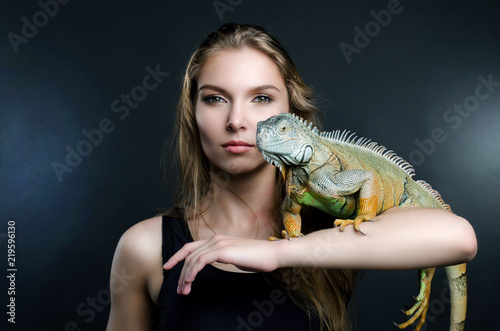perfect portrait beautiful girl and green iguana in the studio
