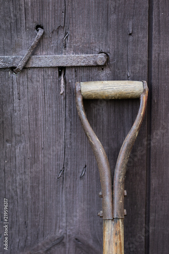 Handle of a shovel and wooden door. Tools for working in the field.