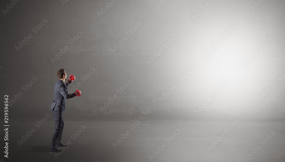 Businessman fighting with boxing gloves in an empty space
