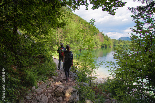 Two people walking along the lakeshore, summer on the lake Bohinj in Slovenia