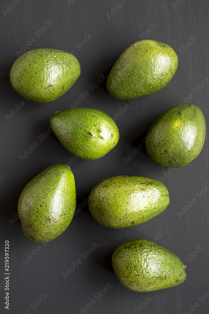 Whole avocados on dark wooden background, top view. Overhead, from above.