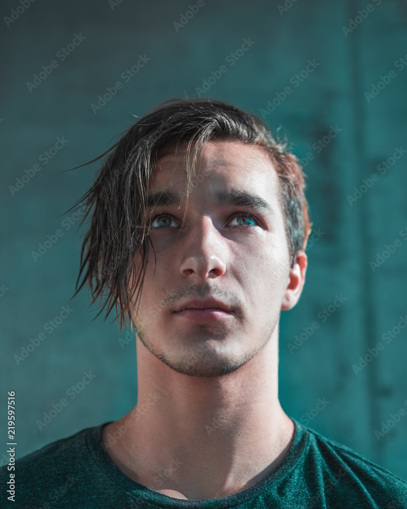 Portrait of a handsome guy with disheveled hair against a gray concrete wall. toned Portrait of a handsome guy with disheveled hair against a gray concrete wall. toned
