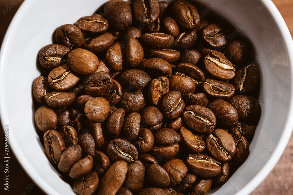 Naklejka premium Cup of Coffee Beans roasted on a wooden table with fresh bean with great aroma