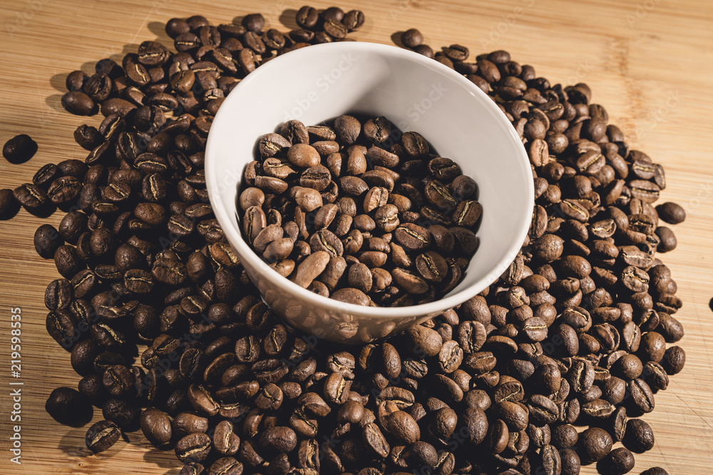 Fototapeta premium Cup of Coffee Beans roasted on a wooden table with fresh bean with great aroma