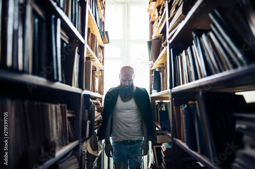 Man bowed head between bookshelves