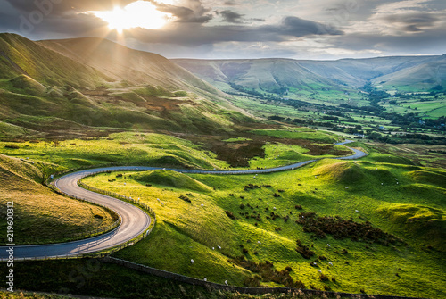 Fotografie, Obraz Sunset at Mam Tor, Peak District National Park, with a view along the winding road among the green hills down to Hope Valley, in Derbyshire, England