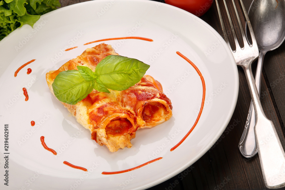 Caneloni stuffed with meat and melted cheese on white plate