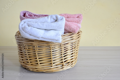 Wicker basket with towels on a light background