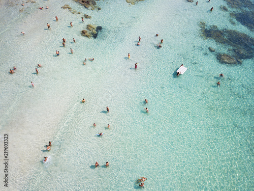 Aerial view of relaxed people swimming on a clear and transparent sea. Cala Brandinchi, Sardinia, Italy.