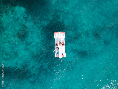 Aerial view of some relaxed people on a pedalos floating on a beautiful turquoise sea. Cala Brandinchi, Sardinia, Italy.