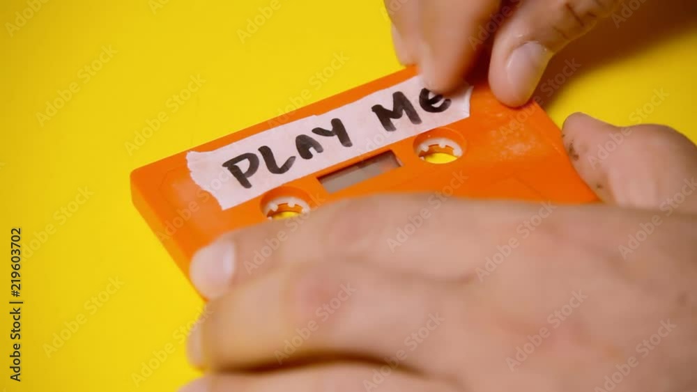 Applying a handwritten label on a vintage cassette tape (obsolete music