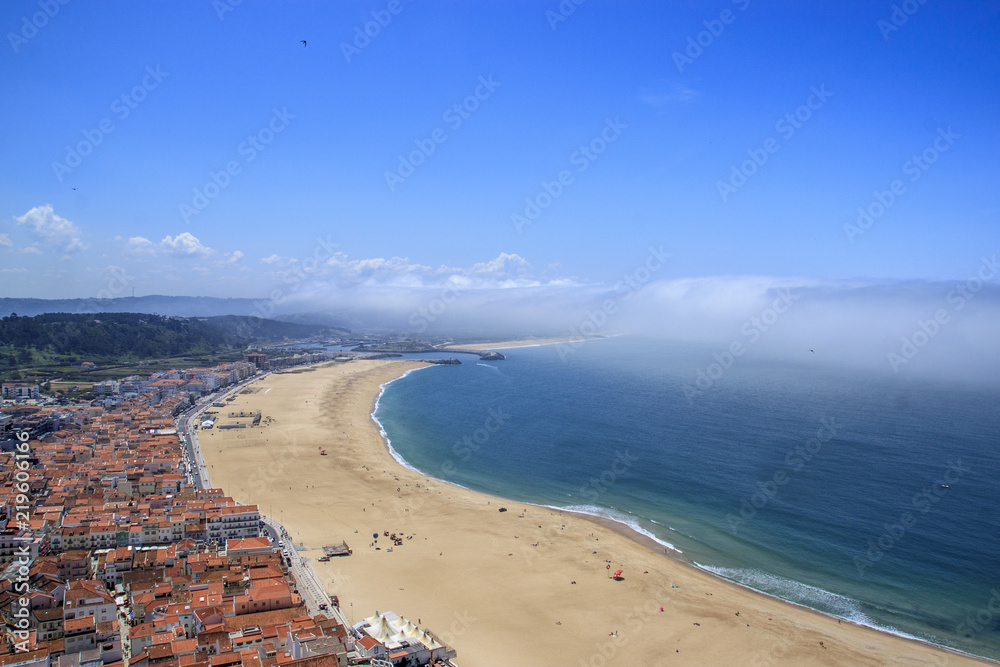 Scenic view of Nazare beach, Portugal. Coastline of Atlantic ocean. Portuguese seaside town on Silver coast. The clouds above the water like tsunami waves.