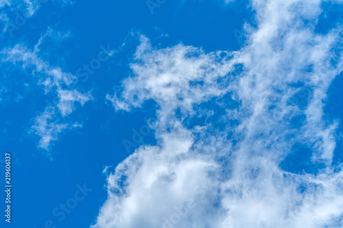 Light fluffy clouds against a bright blue sky background