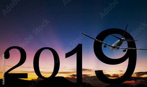 Silhouette 2019 text at beautiful light in sunset or sunrise with airplane take off in the sky.