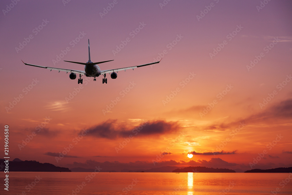 Airplane flying over tropical sea at beautiful sunset or sunrise scenery background,Beautiful sweet purple color scenery view of seascape in phuket thailand.