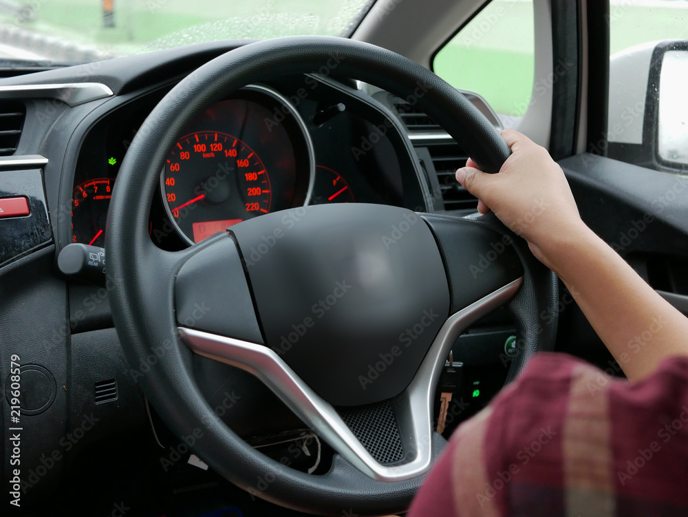 Selective focus of woman hand on steering wheel driving a car with one hand