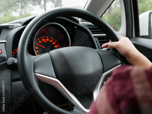 Selective focus of woman hand on steering wheel driving a car with one hand