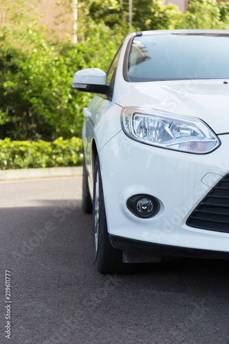 Closeup of a white car head driving on an outdoor road © 宗毅