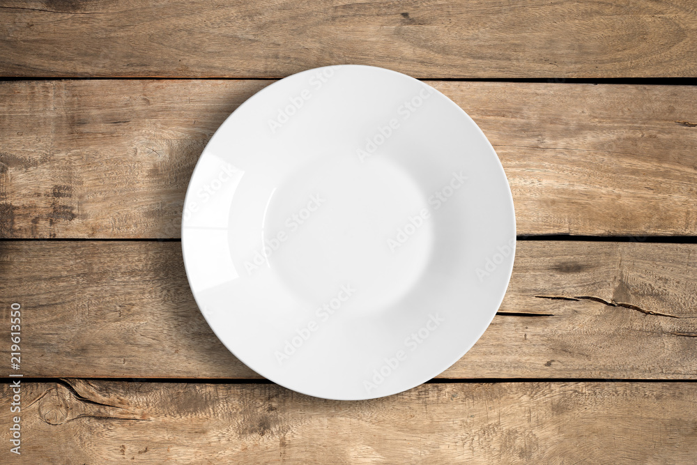 Top view of empty white food plate on a wooden background. Top view of empty white food plate on a wooden background.