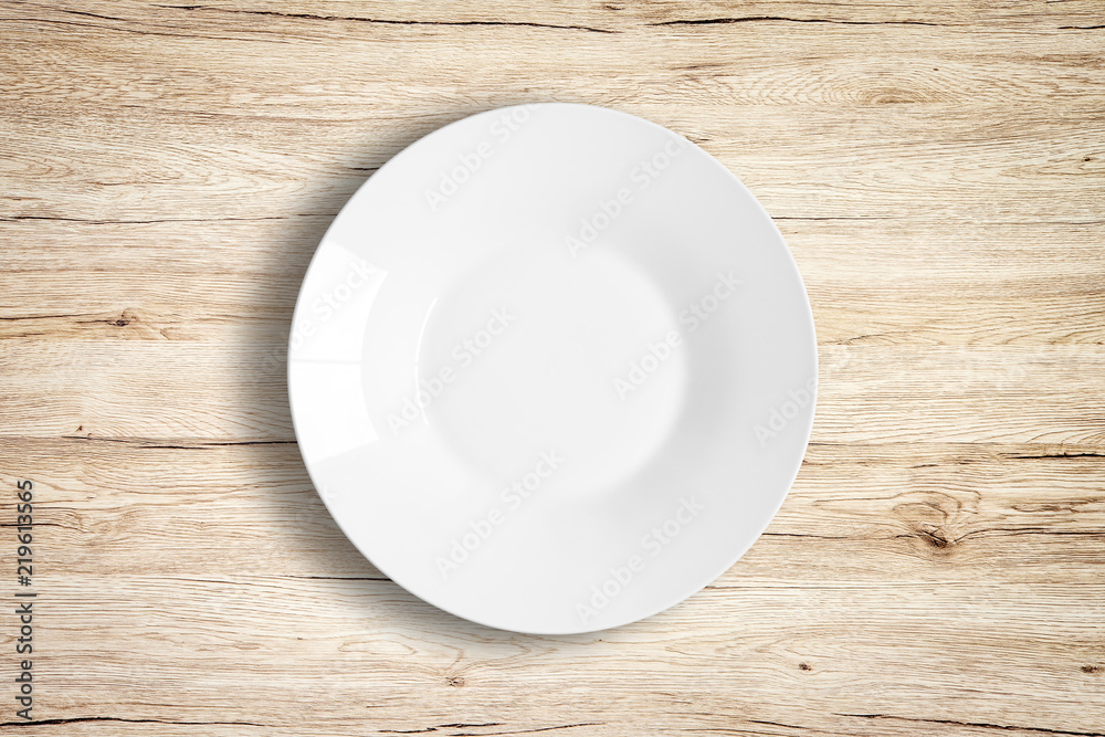Top view of empty white food plate on a wooden background.