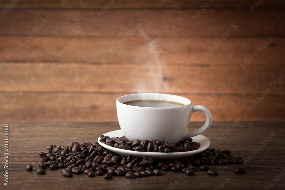 Fototapeta premium A cup of hot coffee on a wooden table with roasted coffee beans