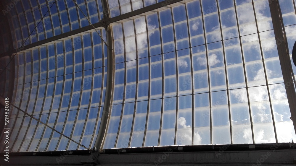 Obraz premium Blick in den blauen Himmel durch ein Dach eines großen Gewächshauses oder auch Tropenhaus