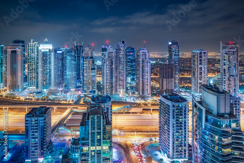 Scenic nighttime skyline of big modern city. Aerial view on skyscrapers and highways of Dubai Marina  UAE. Multicolored travel background.