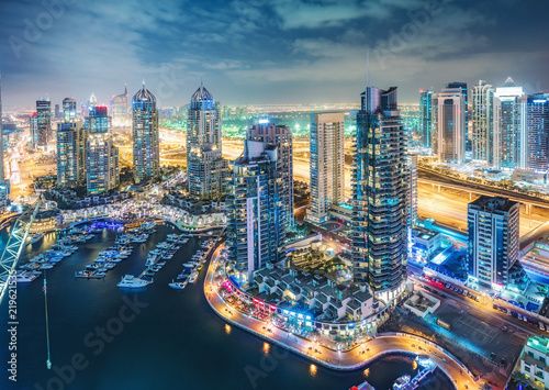 Scenic nighttime skyline of big modern city. Aerial view on skyscrapers and highways of Dubai Marina, UAE. Multicolored travel background.