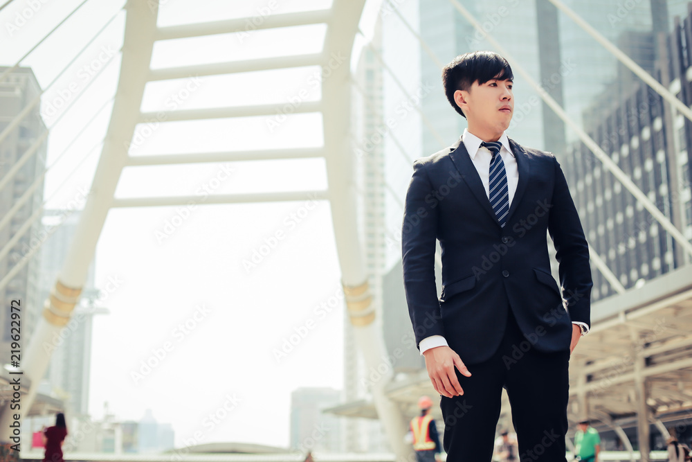 Young businessman confident in suit, adjusting arms and looking out into modern city. Young businessman confident in suit, adjusting arms and looking out into modern city.