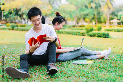 Group of asian university students reading a book the final exam summer on grass field at outdoors.Educational Learning Concepts. photo