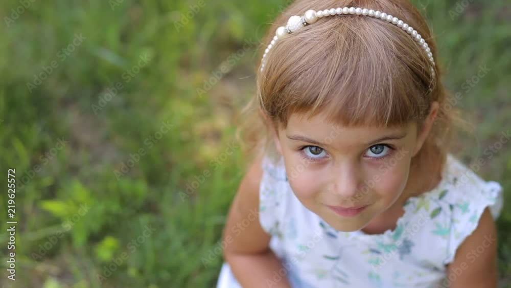 Portrait of a cute little girl in the Park on the grass, her eyes are different colors. Portrait of a small child with heterochromia. Portrait of a cute little girl in the Park on the grass, her eyes are different colors. Portrait of a small child with heterochromia.