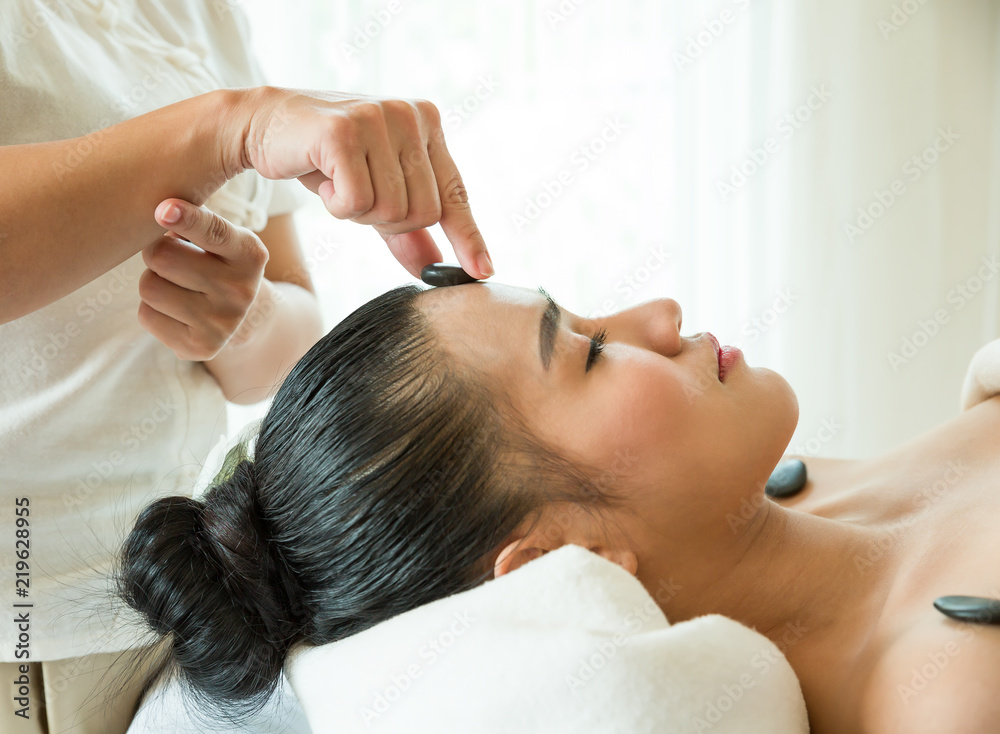 Naklejka premium Beautiful woman lying in spa salon and enjoying face massage, Health care concept.