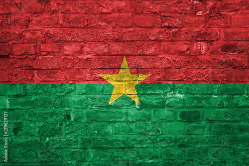 Flag of Burkina Faso over an old brick wall background, surface