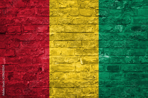 Flag of Guinea over an old brick wall background, surface