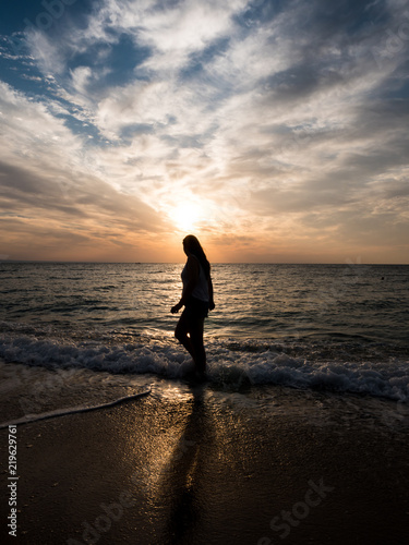 Young woman towards the beautiful sunset on the sea beach. Enjoying the moment