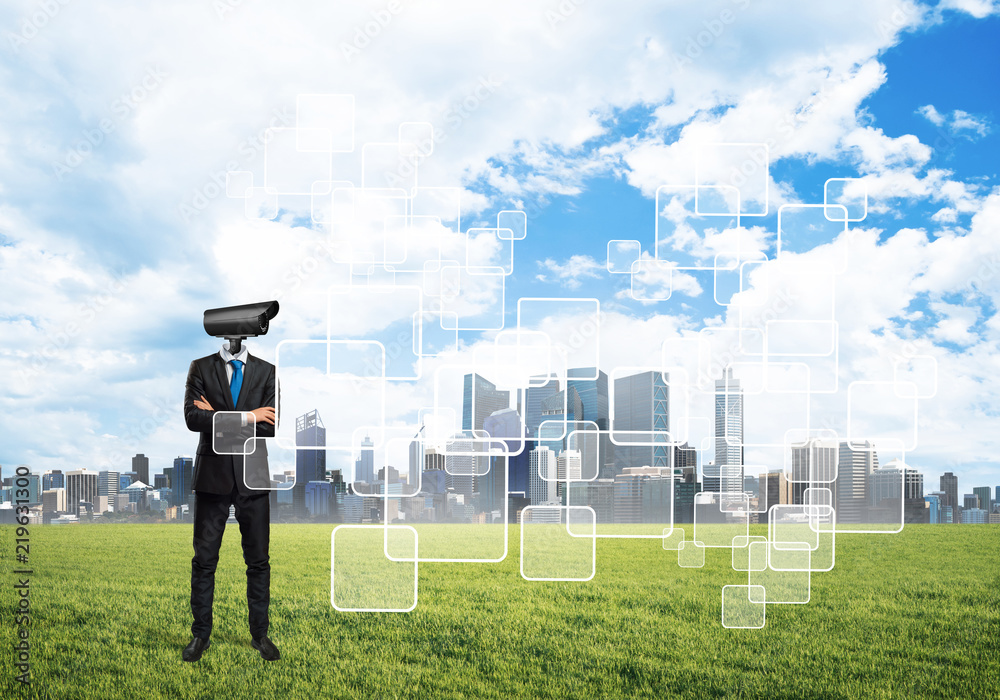 Camera headed man standing on green grass against modern cityscape Camera headed man standing on green grass against modern cityscape