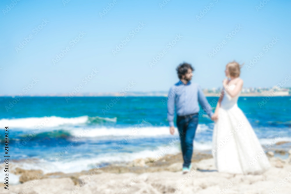 Blurred photo of a couple of newlyweds on a beach near the sea. Blurred photo of a couple of newlyweds on a beach near the sea.