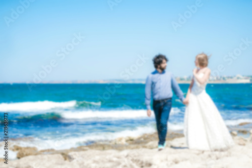 Blurred photo of a couple of newlyweds on a beach near the sea.