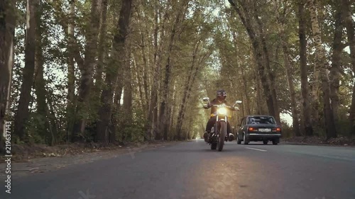 Wallpaper Mural A guy in a black leather jacket and helmet riding a classic motorcycle on a forest road. Close-up on the side. The guy is riding a motorcycle. Torontodigital.ca