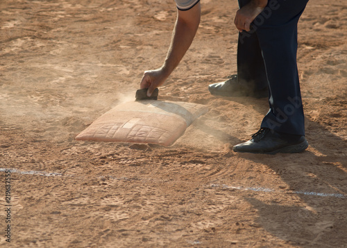 Referee cleans home plate in a baseball (softball) dusty field, with copyspace