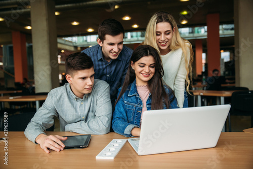 Group of college students studying in the school library, a girl and a boy are using a laptop and connecting to internet