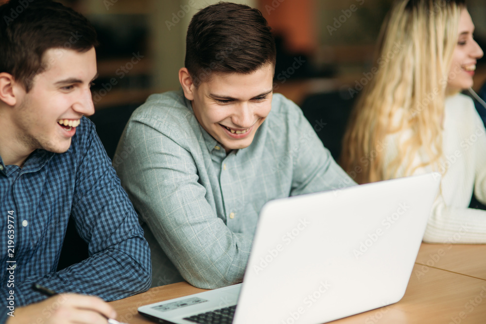 Group of college students studying in the school library, a girl and a boy are using a laptop and connecting to internet Group of college students studying in the school library, a girl and a boy are using a laptop and connecting to internet