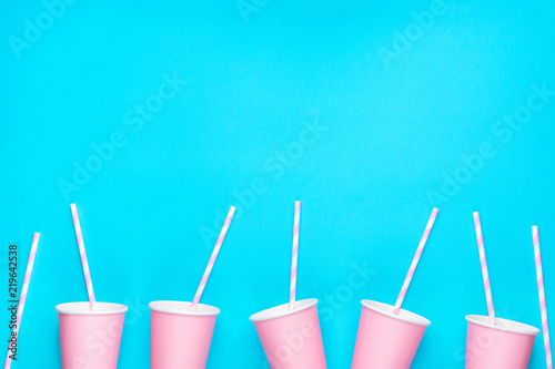 Canvas Print Row of pink empty paper cups striped drinking straws arranged in bottom border on mint blue background
