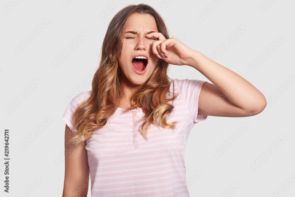 Depressed young woman scream loudly after seeing nightmare at night, keeps mouth widely opened, dressed in casual t shirt, isolated over white background. Female after having dreadful dreams Depressed young woman scream loudly after seeing nightmare at night, keeps mouth widely opened, dressed in casual t shirt, isolated over white background. Female after having dreadful dreams