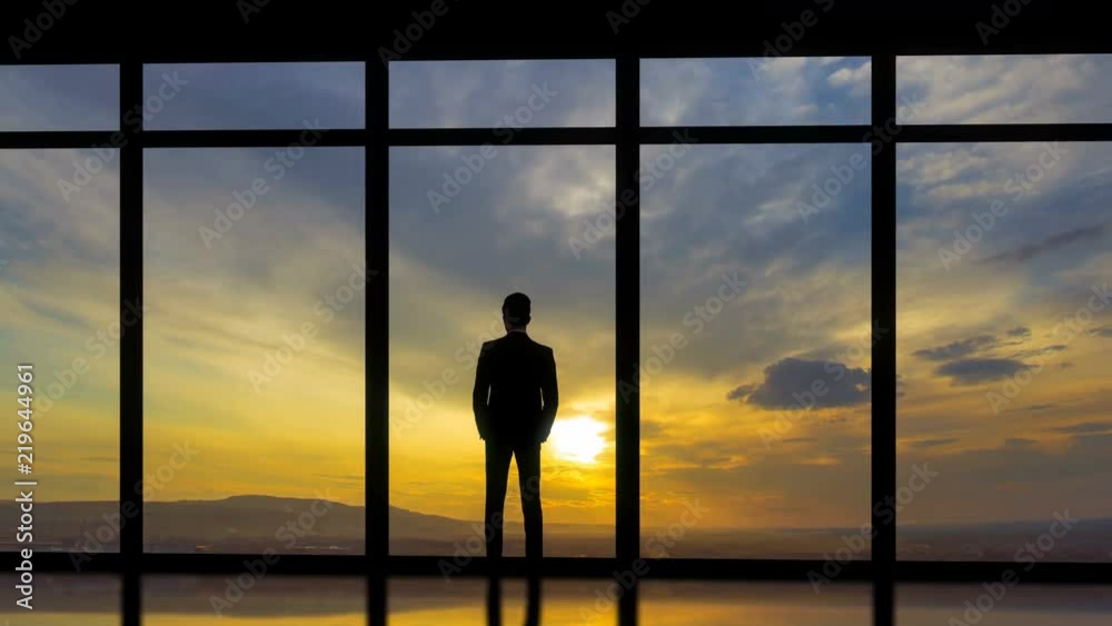 The man standing near windows on the sunset background. time lapse