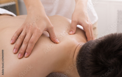 Masseur doing back massage on man body