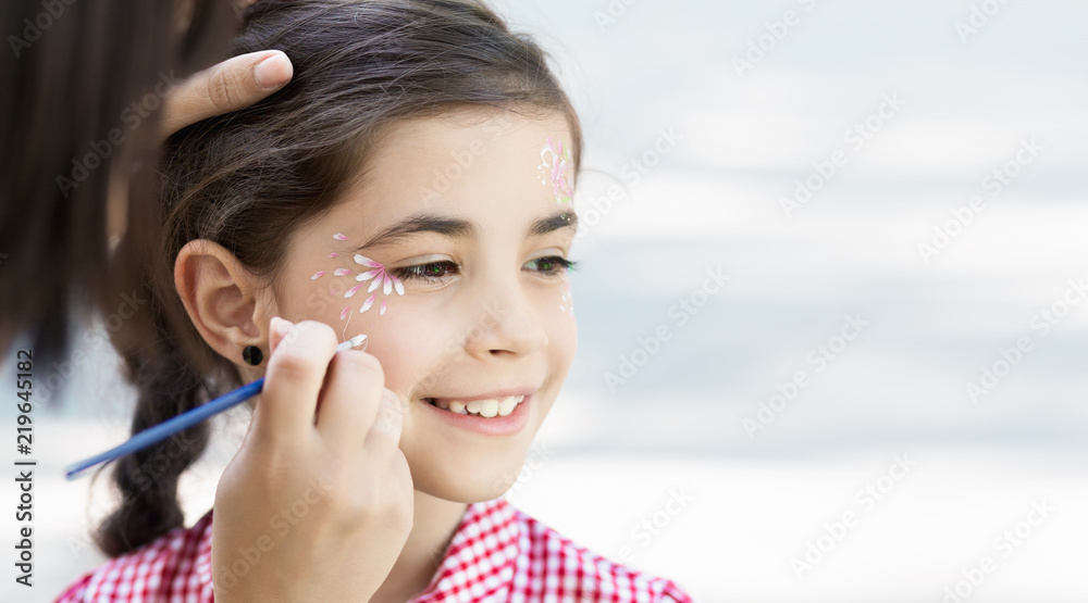 Little girl getting her face painted by face painting artist. Little girl getting her face painted by face painting artist.