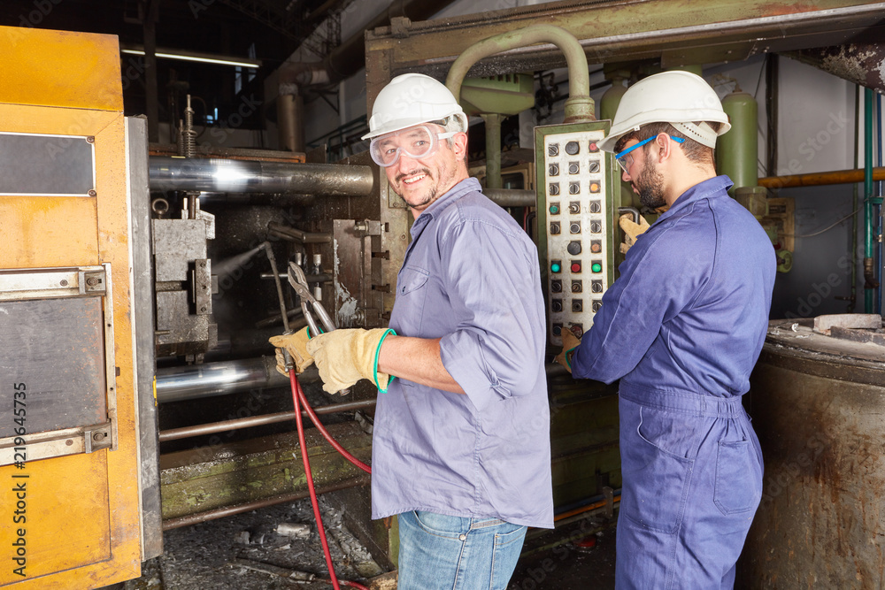Arbeiter bedienen ein Steuerpult in Metallfabrik