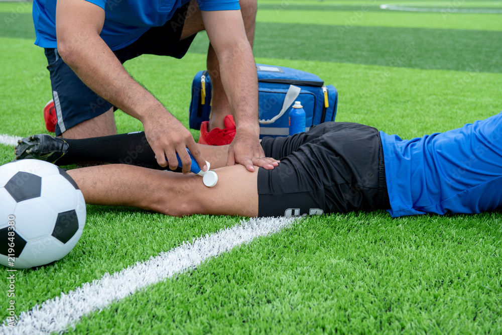 Fototapeta premium Footballer wearing a blue shirt, black pants injured in the lawn during the race.