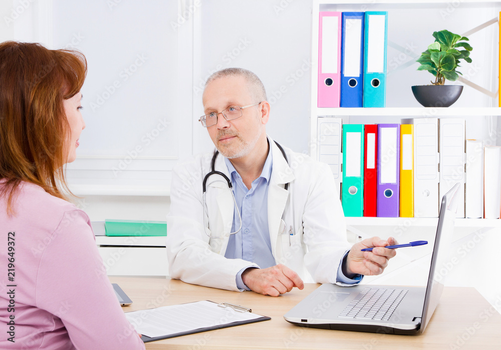 Doctor is talking with woman patient and sitting in medical office.Man in white uniform. Medical insurance. Copy space. Quality medicine concept. Doctor is talking with woman patient and sitting in medical office.Man in white uniform. Medical insurance. Copy space. Quality medicine concept.
